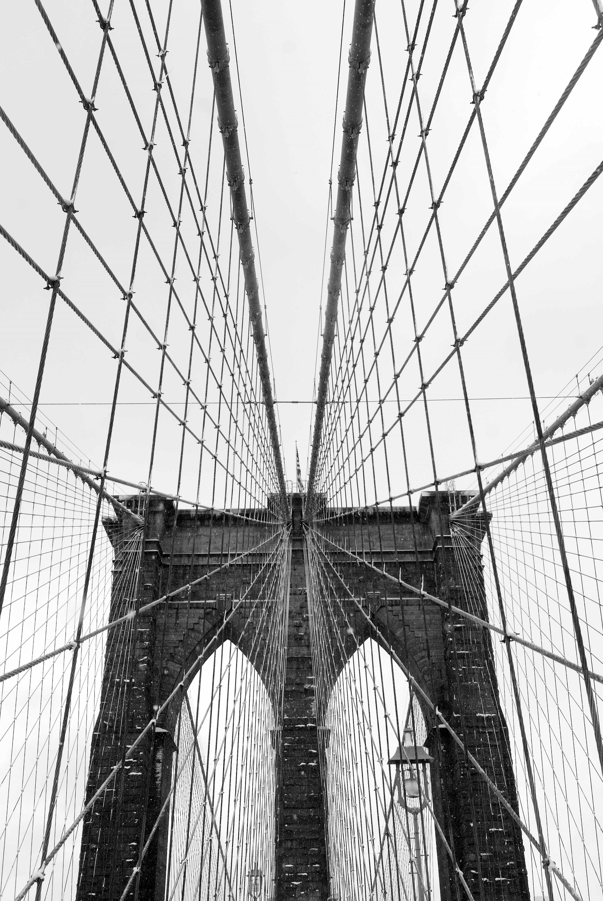An image that encompasses the geometry and architectural beauty of New Yorks Brooklyn Bridge