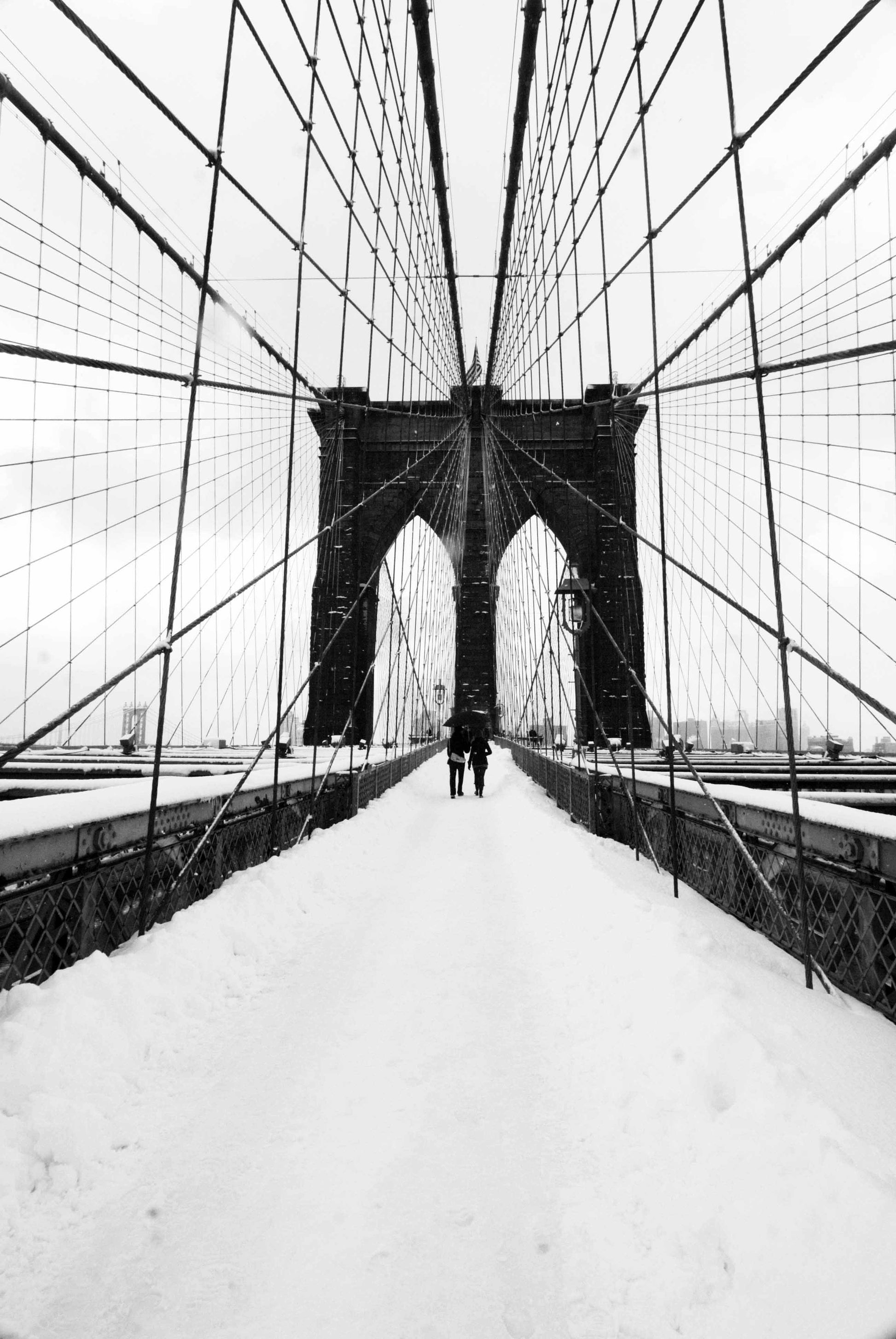 Alessandra Mattanza | INFINITY OF LOVE, New York. Lovers meet on a snowy Brooklyn Bridge. Available as an art print or photographic print on acrylic glass.